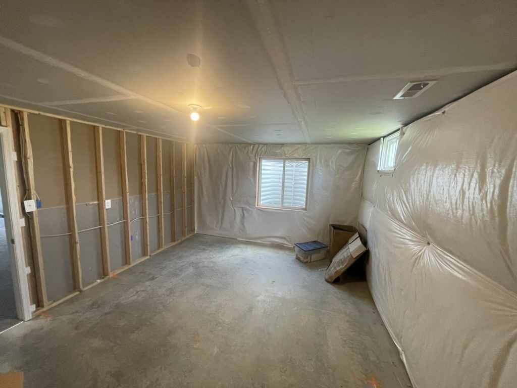 Basement mid-project with framed stud walls and vapor barrier over a concrete floor