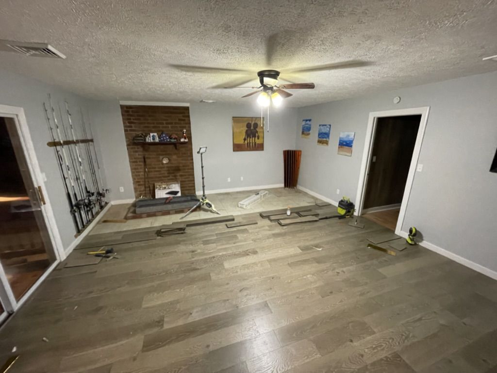 Family room during flooring installation with planks and tools on the floor