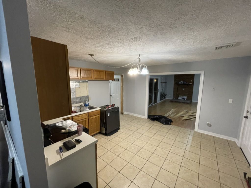 Kitchen and dining area before: oak cabinets, beige tile, and a chandelier, looking toward the family room